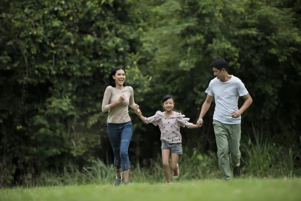 Happy family is having fun Mother, father and daughter are running in park.